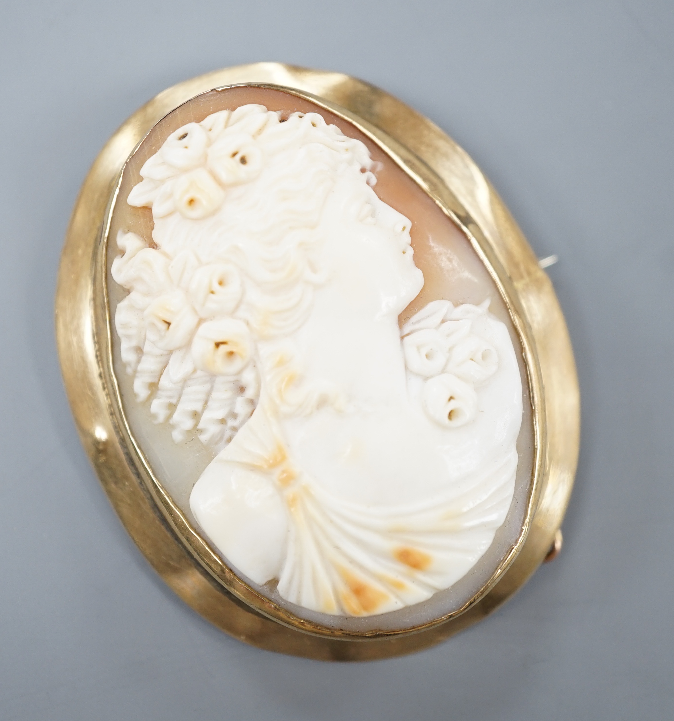 A yellow metal mounted oval cameo shell brooch, carved with the bust of a lady to sinister, 51mm, gross 16 grams.